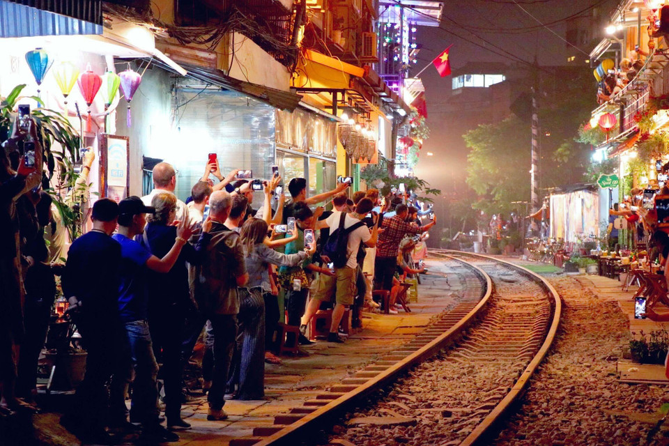 Khi đoàn tàu xuất hiện cũng là lúc tất cả camera, máy ảnh, điện thoại được sử dụng hết công suất, du khách reo hò vui vẻ khiến cho bầu không khí nơi xóm nhỏ trở nên ồn ã đến lạ thường. (Ảnh: Vi Thương-Hải Yến/TTXVN)