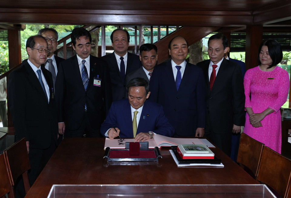 Thủ tướng Nguyễn Xuân Phúc và Thủ tướng Nhật Bản Suga Yoshihide tham quan Nhà sàn Bác Hồ trong Khu Di tích Chủ tịch Hồ Chí Minh tại Phủ Chủ tịch. (Ảnh: Thống Nhất/TTXVN)