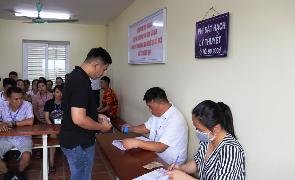 Học viên làm thủ tục đóng lệ phí trước khi vào phòng thi. (Ảnh: Việt Hùng/Vietnam+)