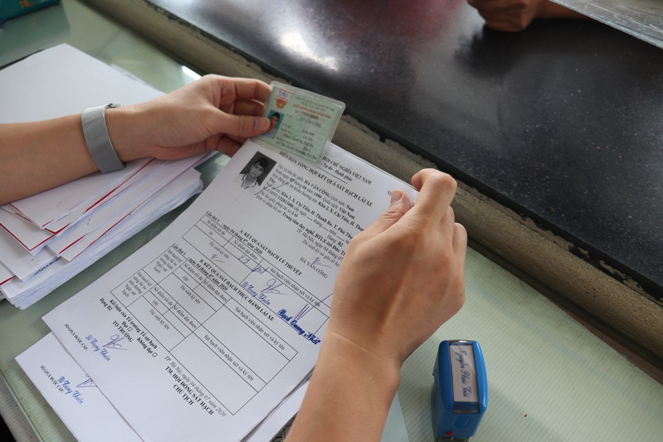 Kiểm tra kỹ càng họ và tên trên chứng minh nhân dân với tờ biên bản thi nhằm đúng học viên tham dự kỳ thi. (Ảnh: Việt Hùng/Vietnam+)