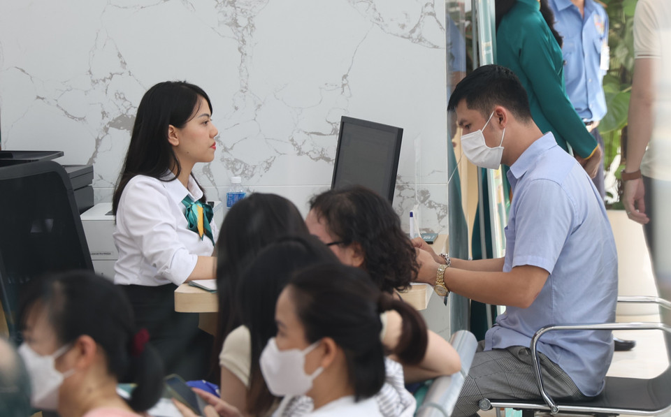 Người dân đang được các giao dịch viên hướng dẫn thủ tục mua vàng. (Ảnh: PV/Vietnam+)