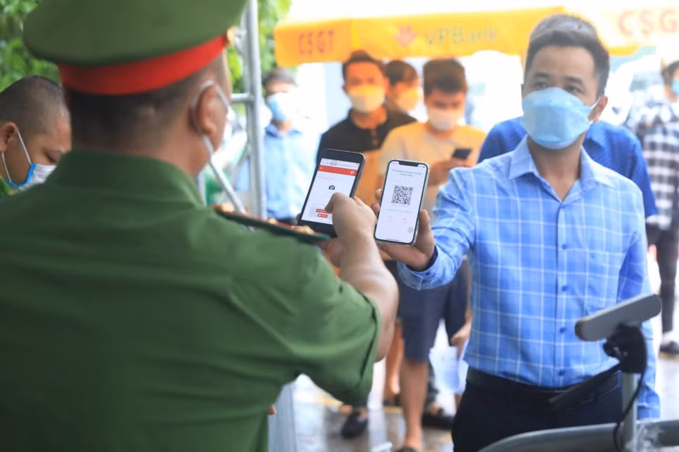 Lực lượng chức năng kiểm tra mã QR của người dân tại chốt kiểm soát dịch cầu Phù Đổng. (Ảnh: Tuấn Anh/TTXVN)
