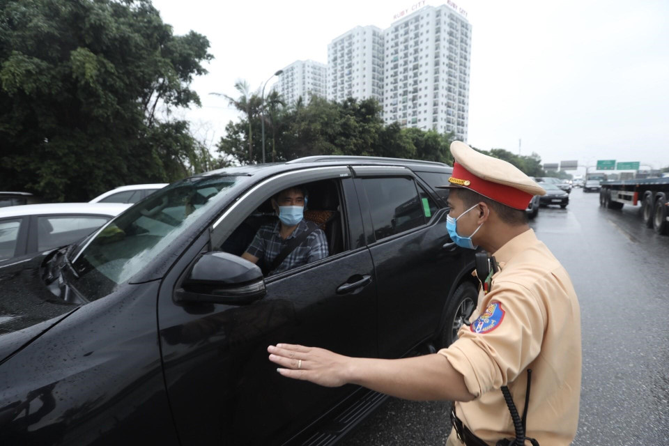 Lực lượng chức năng yêu cầu người tham gia giao thông dừng phương tiện, kiểm tra giấy tờ trước khi vào nội đô tại chốt kiểm soát cầu Phù Đổng (huyện Gia Lâm). (Ảnh: Minh Quyết/TTXVN)
