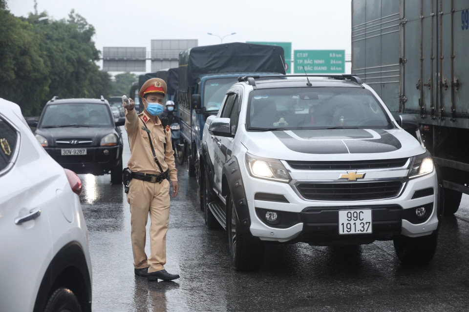 Lực lượng chức năng yêu cầu người tham gia giao thông dừng phương tiện, kiểm tra giấy tờ trước khi vào nội đô tại chốt kiểm soát cầu Phù Đổng (huyện Gia Lâm). (Ảnh: Minh Quyết/TTXVN)