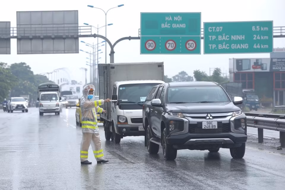 Lực lượng chức năng yêu cầu người tham gia giao thông dừng phương tiện, kiểm tra giấy tờ trước khi vào nội đô tại chốt kiểm soát cầu Phù Đổng (huyện Gia Lâm). (Ảnh: Minh Quyết/TTXVN)