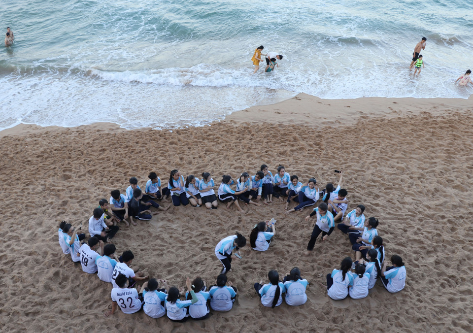 Khu vực bãi biển gần Tháp Nghinh Phong thu hút đông các bạn trẻ đến vui chơi. (Ảnh: Phạm Cường/TTXVN)
