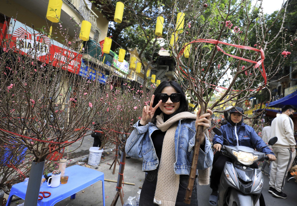 Niềm vui khi mua được cành đào ưng ý. (Ảnh: Nhật Anh/TTXVN)