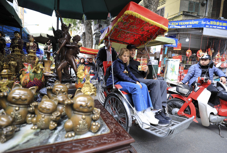 Du khách thích thú với cung đường tham quan qua chợ hoa Hàng Lược. (Ảnh: Nhật Anh/TTXVN)