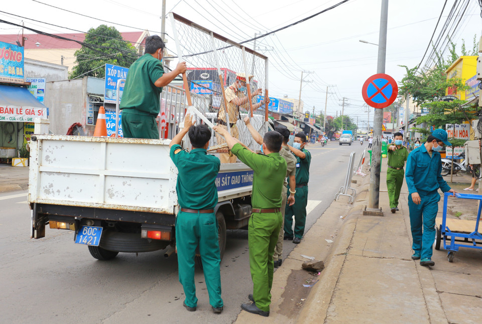 Lực lượng chức năng thực hiện dỡ bỏ phong tỏa cho 20 hộ dân tại khu phố 2, phường Xuân Thanh. (Ảnh: Lê Xuân/TTXVN)