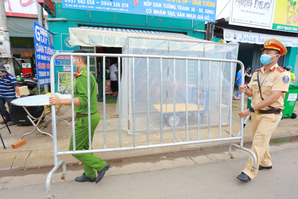 Lực lượng chức năng thực hiện dỡ bỏ phong tỏa cho 20 hộ dân tại khu phố 2, phường Xuân Thanh. (Ảnh: Lê Xuân/TTXVN)