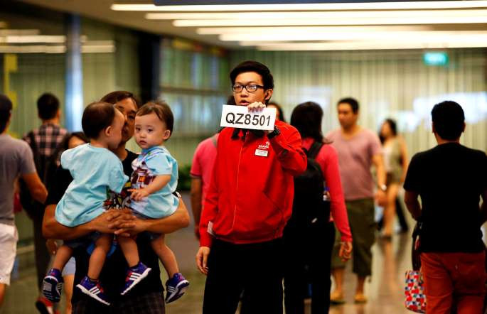 Một nhân viên sân bay Changi cầm tấm biển để đón thân nhân hành khách có mặt trên chuyến bay QZ8501. (Nguồn: Reuters)