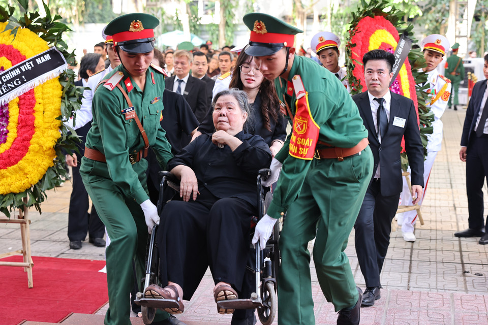 Lực lượng kiểm soát quân sự hỗ trợ, giúp bà Đặng Thị Phúc, giáo viên tiểu học của Tổng Bí thư Nguyễn Phú Trọng, năm nay đã 92 tuổi, sức khỏe đã giảm nhiều, đến Nhà tang lễ Quốc gia số 5 Trần Thánh Tông để được tiễn biệt học trò lần cuối. (Ảnh: TTXVN)