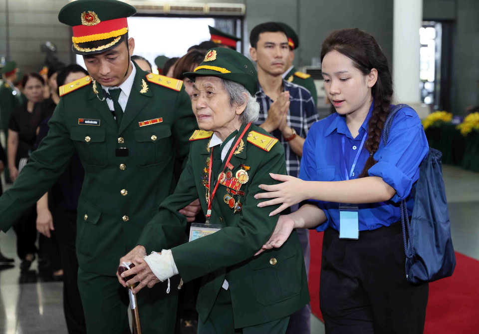 Lực lượng quân đội và thanh niên tình nguyện hỗ trợ một nữ cựu chiến binh vào viếng Tổng Bí thư Nguyễn Phú Trọng. (Ảnh: TTXVN)