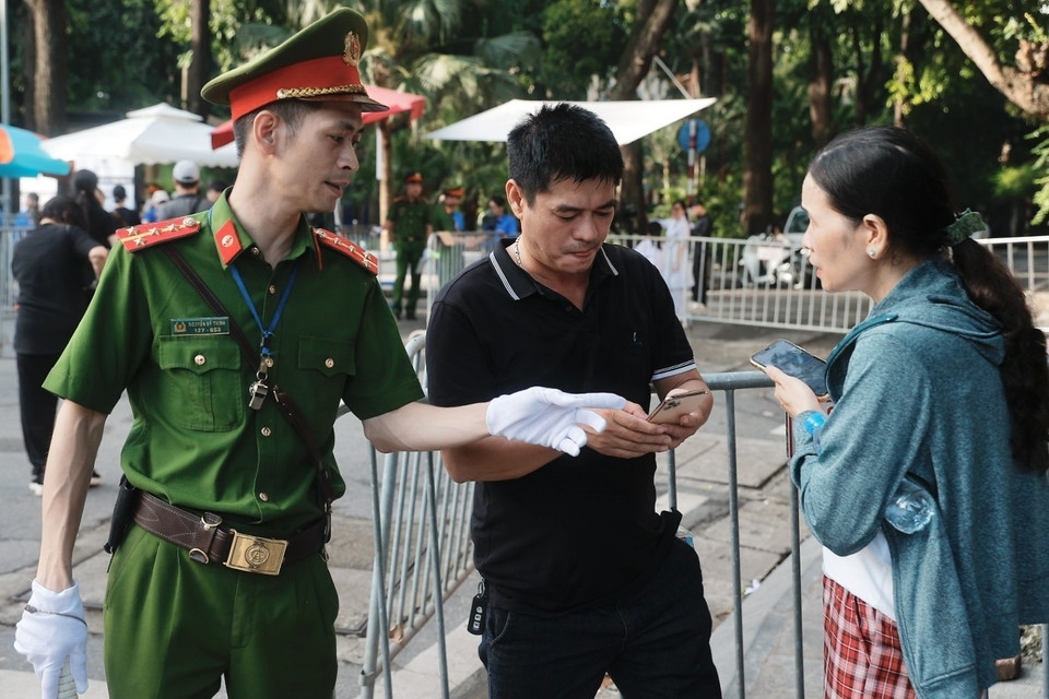 Công an hỗ trợ, hướng dẫn người dân cài đặt ứng dụng VNeID, quét mã QR khi vào viếng Tổng Bí thư Nguyễn Phú Trọng. (Ảnh: Minh Quyết/ TTXVN)