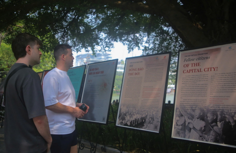 Du khách quốc tế xem triển lãm ảnh và tư liệu lịch sử về 70 năm ngày Giải phóng Thủ đô được trưng bày tại khu vực hồ Hoàn Kiếm. (Ảnh: Quỳnh Anh/TTXVN phát)
