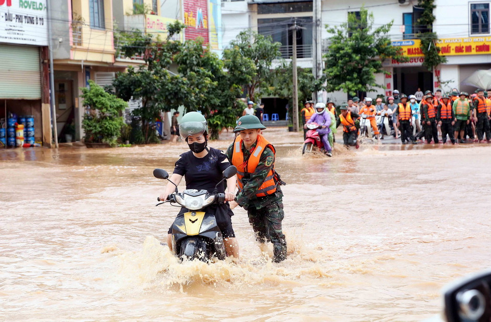 Bộ đội hỗ trợ người dân di chuyển qua khu vực bị ngập lụt tại thành phố Sơn La. (Ảnh: Quang Quyết/TTXVN)