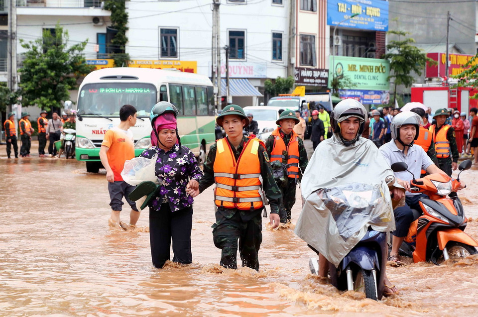 Bộ đội hỗ trợ người dân di chuyển qua khu vực bị ngập lụt tại thành phố Sơn La. (Ảnh: Quang Quyết/TTXVN)