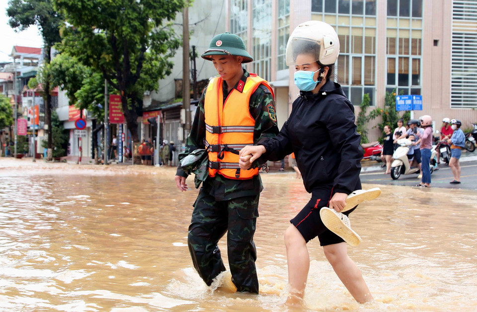 Bộ đội hỗ trợ người dân di chuyển qua khu vực bị ngập lụt tại thành phố Sơn La. (Ảnh: Quang Quyết/TTXVN)