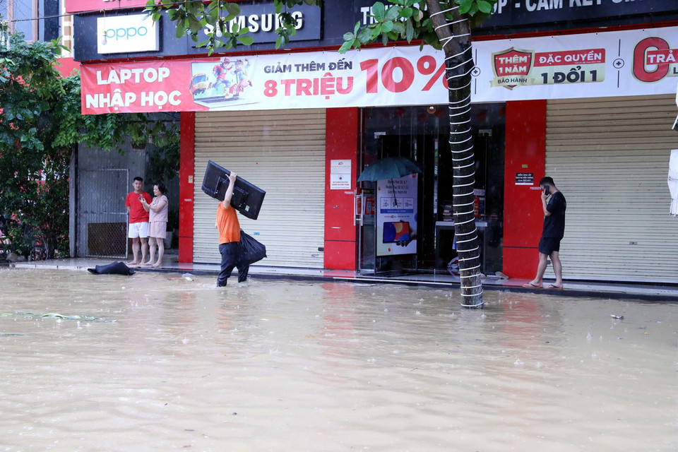 Người dân di chuyển tài sản đến nơi khô ráo. (Ảnh: Quang Cường/TTXVN)