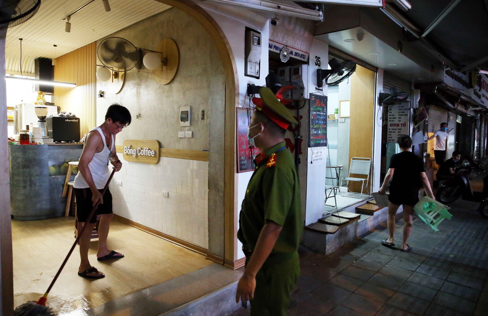 Công an phường Lê Đại Hành, quận Hai Bà Trưng nhắc nhở các hộ kinh doanh Cafe tại phố Thái Phiên đóng cửa đúng giờ quy định và cam kết chỉ bán đồ mang về từ ngày 13/7/2021. (Ảnh: Phạm Kiên/TTXVN)