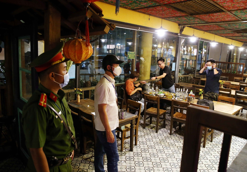 Công an phường Lê Đại Hành, quận Hai Bà Trưng nhắc nhở hộ kinh doanh ăn uống tại phố Hoa Lư đóng cửa đúng giờ quy định và cam kết chỉ bán đồ mang về bắt đầu từ ngày 13/7/2021. Hà Nội. (Ảnh: Phạm Kiên/TTXVN)