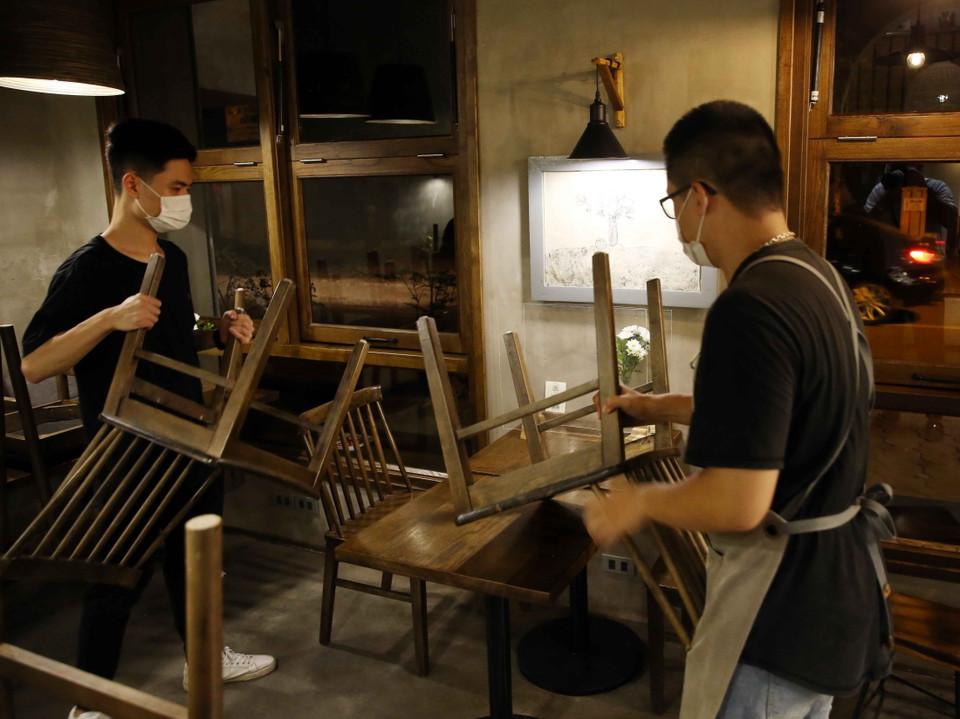 Nhân viên quán Cafe trên phố Hồ Xuân Hương, phường Nguyễn Du, Quận Hai Bà Trưng thu dọn bàn ghế và bắt đầu hình thức kinh doanh chỉ bán đồ mang về bắt đầu từ ngày 13/7/2021. (Ảnh: Phạm Kiên/TTXVN)