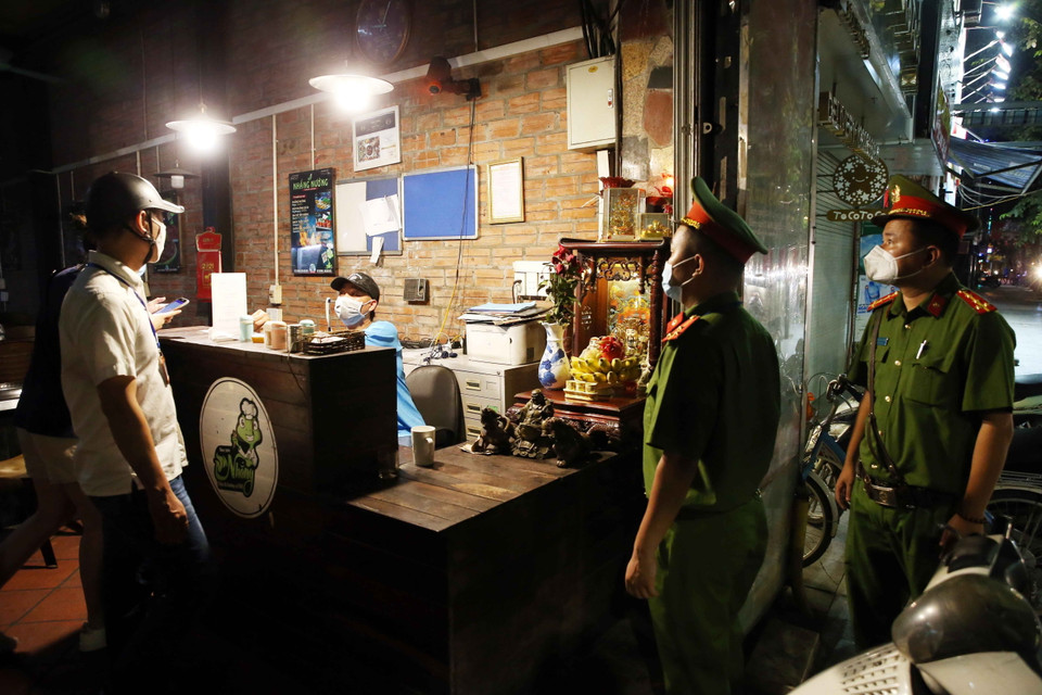 Công an phường Lê Đại Hành, quận Hai Bà Trưng nhắc nhở hộ kinh doanh ăn uống tại phố Đại Cồ Việt đóng cửa đúng giờ quy định và cam kết chỉ bán đồ mang về bắt đầu từ ngày 13/7/2021. (Ảnh: Phạm Kiên/TTXVN)