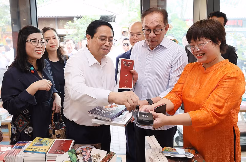 Thủ tướng Phạm Minh Chính mua sách tặng Thủ tướng Malaysia Anwar Ibrahim và Phu nhân. (Ảnh: Dương Giang/TTXVN)