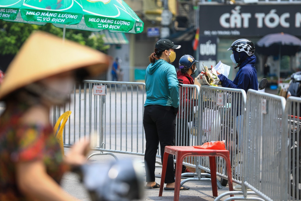 Người dân tại "ổ dịch" phường Văn Chương đã được ra khỏi nhà nhận nhu yếu phẩm nhưng vẫn phải tuân thủ giãn cách theo hướng dẫn của lực lượng chức năng. (Ảnh: Thành Đạt/TTXVN)