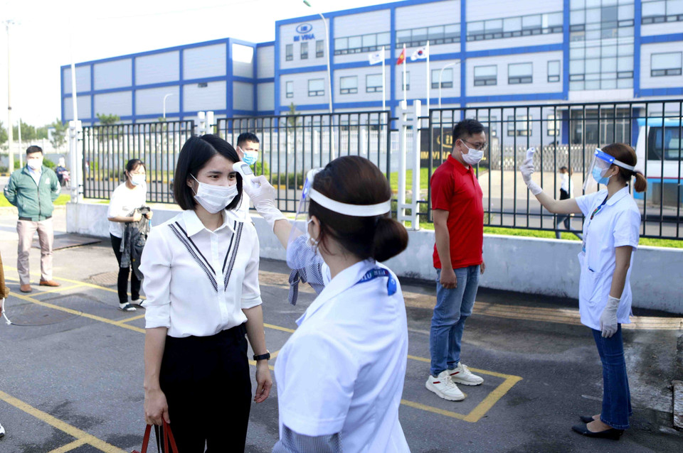 Công nhân và khách vào làm việc tại công ty TNHH Optrontec Vina (khu công nghiệp Bá Thiện 2-Vĩnh Phúc) được kiểm tra thân nhiệt. (Ảnh: TTXVN)