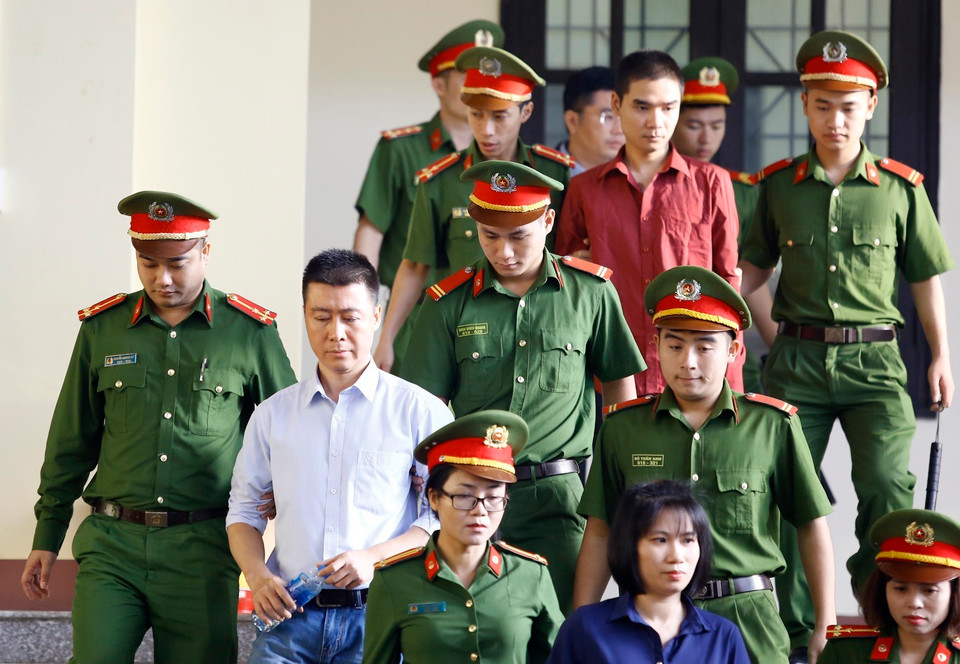 Bị cáo Phan Sào Nam (áo trắng) cùng các bị cáo được cơ quan chức năng dẫn giải ra tòa. (Ảnh: Trung Kiên/TTXVN)