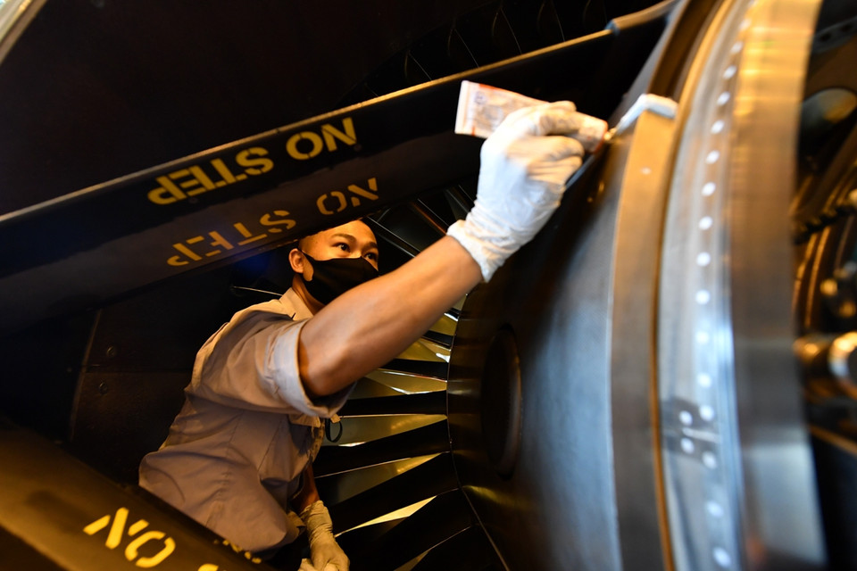 Một số nhân viên khác đang kiểm tra ốc vít và sơn của động cơ máy bay Airbus A350. (Ảnh:Vietnam+)