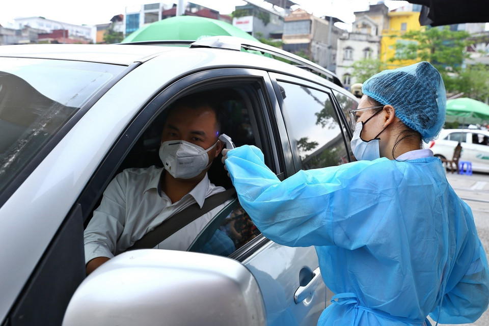 Nhân viên y tế kiểm tra thân nhiệt đối với người vào bệnh viện (ảnh chụp sáng 11/5). (Ảnh: Minh Quyết/TTXVN)