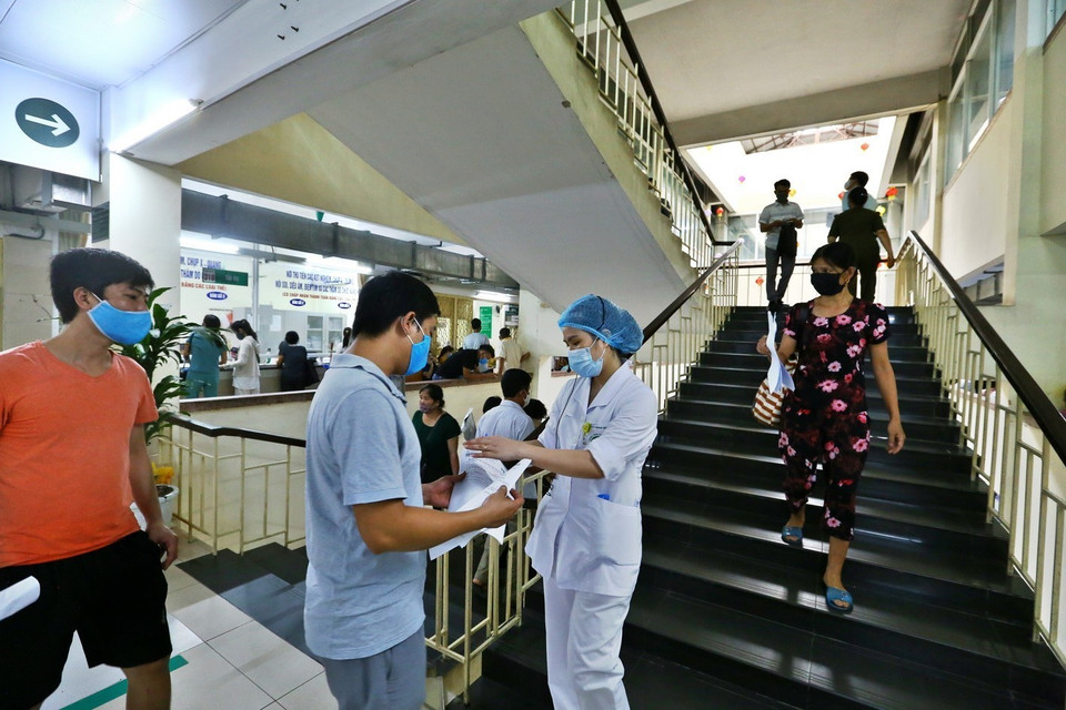 Nhân viên y tế hướng dẫn người dân đến khám bệnh tại các khoa (ảnh chụp sáng 11/5/2020). (Ảnh: Minh Quyết/TTXVN)