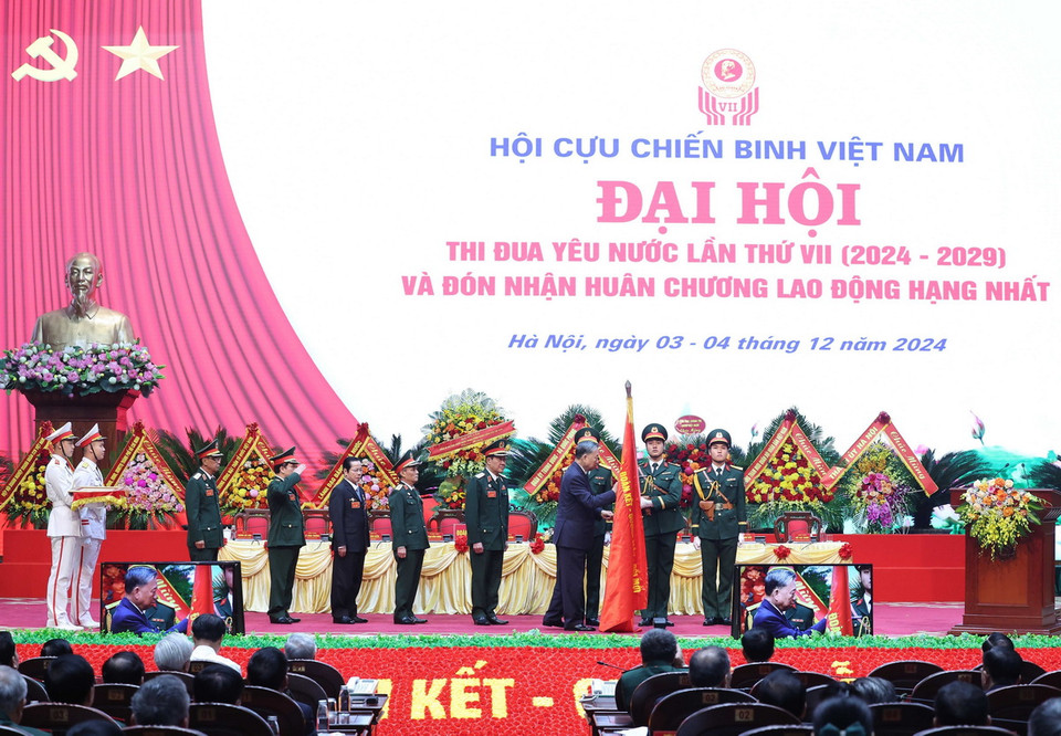 Tổng Bí thư Tô Lâm gắn Huân chương Lao động hạng Nhất lên lá cờ truyền thống Hội Cựu chiến binh Việt Nam. (Ảnh: Thống Nhất/TTXVN)
