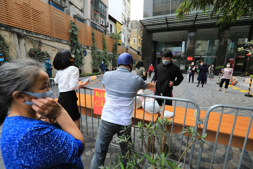 Trước giờ dỡ bỏ cách ly, vẫn còn những người thân mang đồ tiếp tế đến cho gia đình mình. (Ảnh: Thành Đạt/TTXVN)