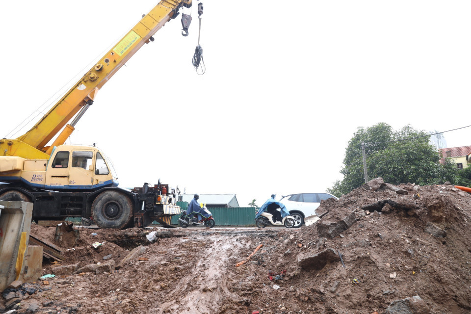 Trời mưa làm vật liệu trong công trường trôi xuống đường dưới chân đê, khiến tuyến đường càng thêm lầy lội. (Ảnh: Huy Hùng/TTXVN)