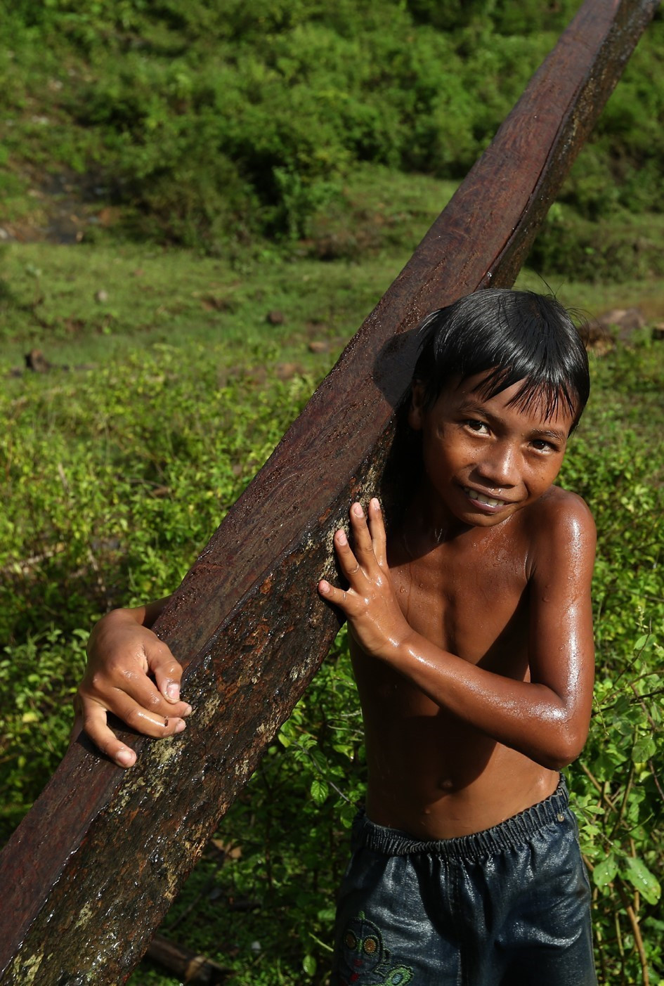 Một cậu bé vớt được thanh củi to trôi dưới sông. (Ảnh: Phan Tuấn Anh/TTXVN)