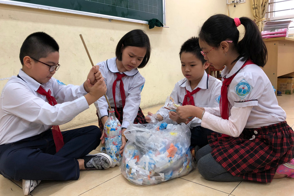 Để làm 'gạch,' các em cắt nhỏ nilon và cho vào chai. Sau đó, dùng que, gậy nhồi chặt nilon rồi cân viên gạch (200gram/chai 500ml) rồi nộp cho Tổng phụ trách vào thứ 5 mỗi tuần.