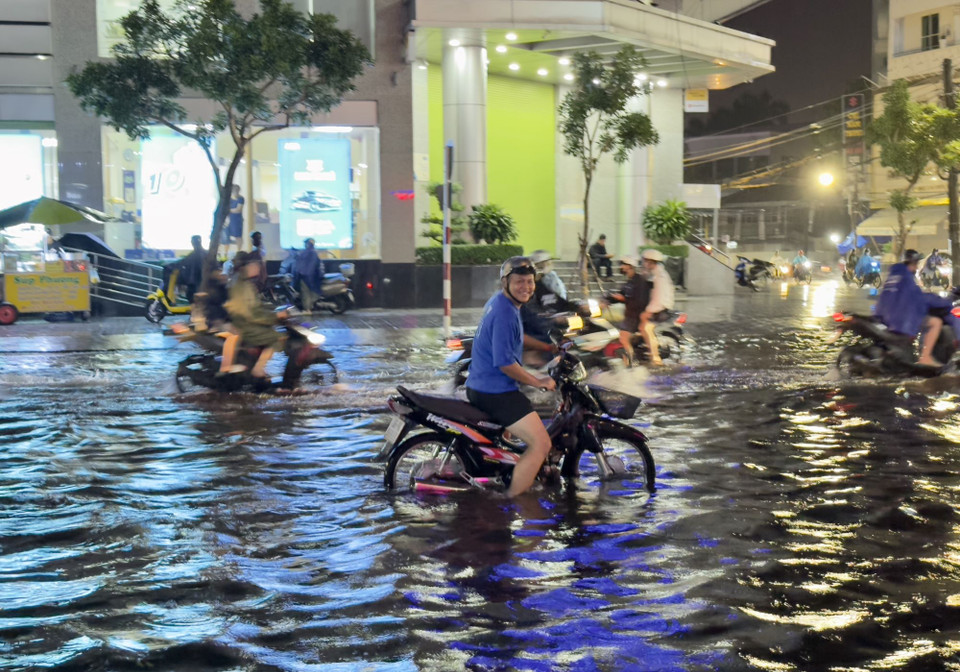 Người dân thành phố Long Xuyên, An Giang vất vả di chuyển qua các tuyến đường ngập sâu trong nước. (Ảnh: Thanh Sang/TTXVN)