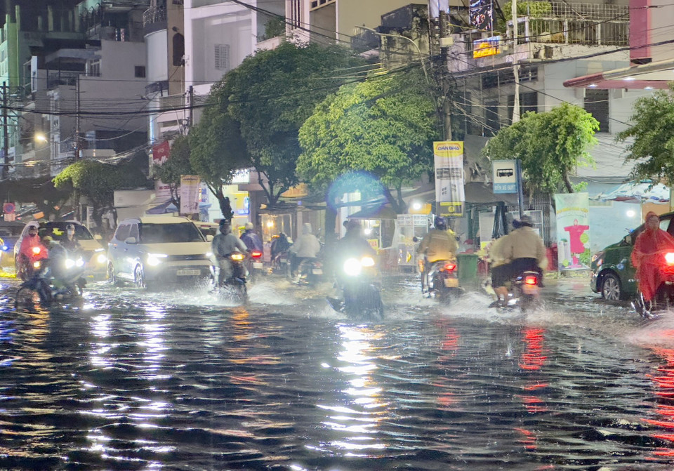Người dân vất vả di chuyển trên đường Hà Hoàng Hổ, thành phố Long Xuyên, An Giang ngập sâu trong nước. (Ảnh: Thanh Sang/TTXVN)