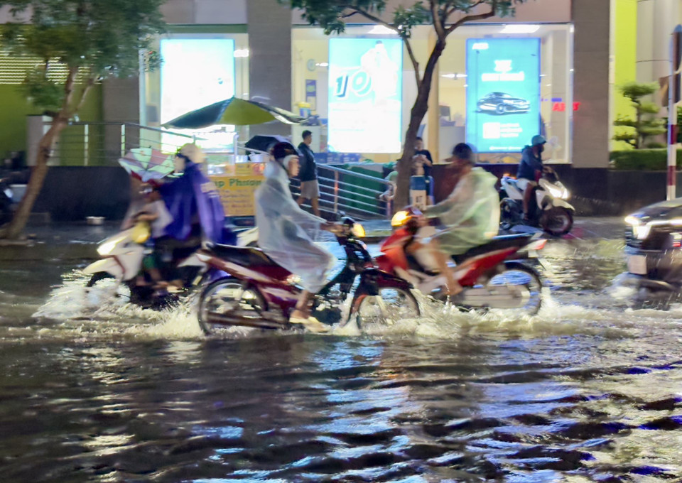 Người dân thành phố Long Xuyên, An Giang vất vả di chuyển qua các tuyến đường ngập sâu trong nước. (Ảnh: Thanh Sang/TTXVN)
