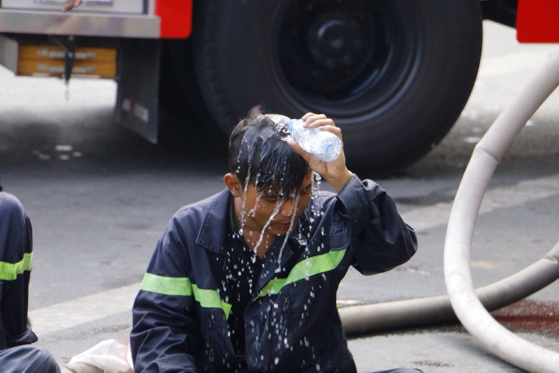 Dội nước lên người để giảm sức nóng từ vụ cháy. (Ảnh: Thanh Liêm/TTXVN)