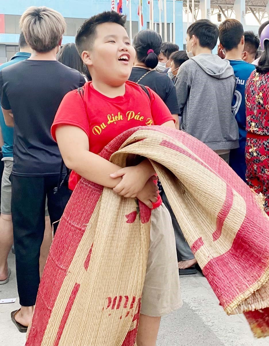 Cổ động viên nhí hào hứng mang chiếu đợi sẵn để nhận vé mời xem trận chung kết. (Ảnh: Thanh Vân/TTXVN)