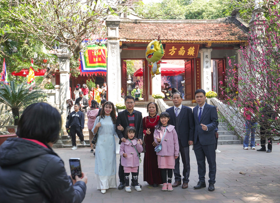 Một gia đình lưu giữ kỷ niệm mùng 3 Tết Giáp Thìn tại đền Kim Liên, nơi thờ thần Cao Sơn Đại vương - trấn ở phía Nam Hà Nội. (Ảnh: Hoàng Hiếu/TTXVN)