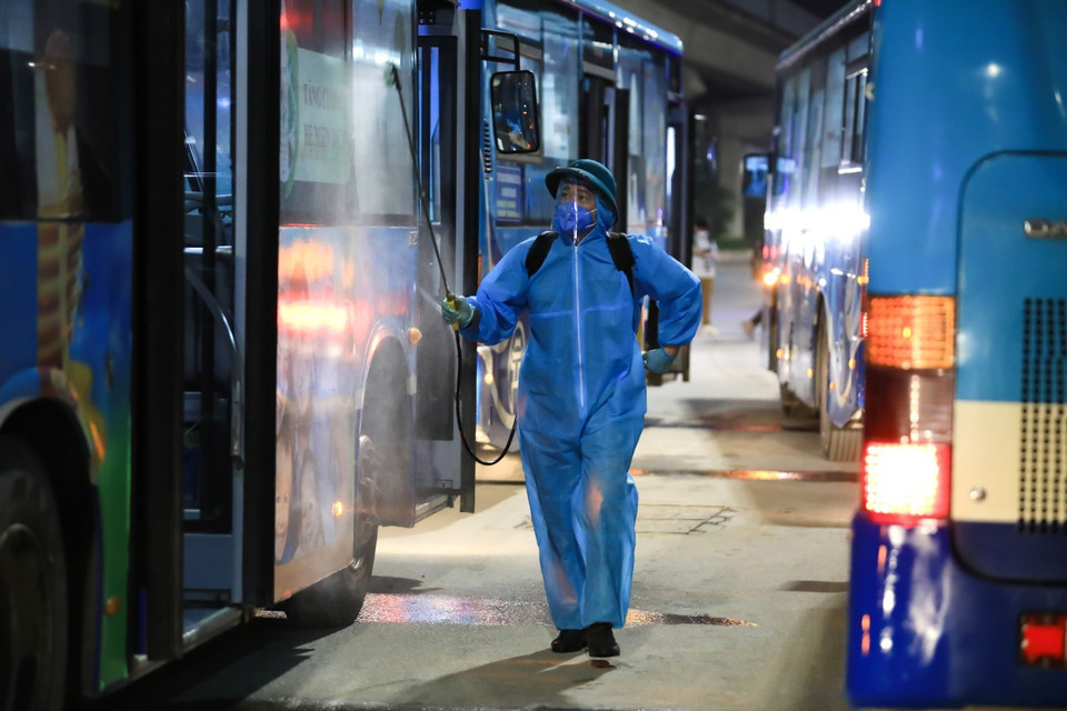  Lực lượng y tế quận Thanh Xuân tiến hành phun khử khuẩn toàn bộ xe buýt đón người dân di dời khỏi ổ dịch.(Ảnh: Thành Đạt/TTXVN)