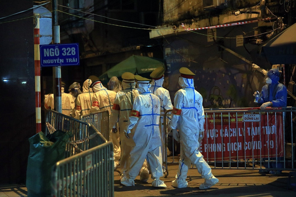 Lực lượng Công an phường Thanh Xuân Trung vào từng hộ dân trong ngõ 328 Nguyễn Trãi gọi và hỗ trợ người dân di chuyển. (Ảnh: Tuấn Anh/TTXVN)