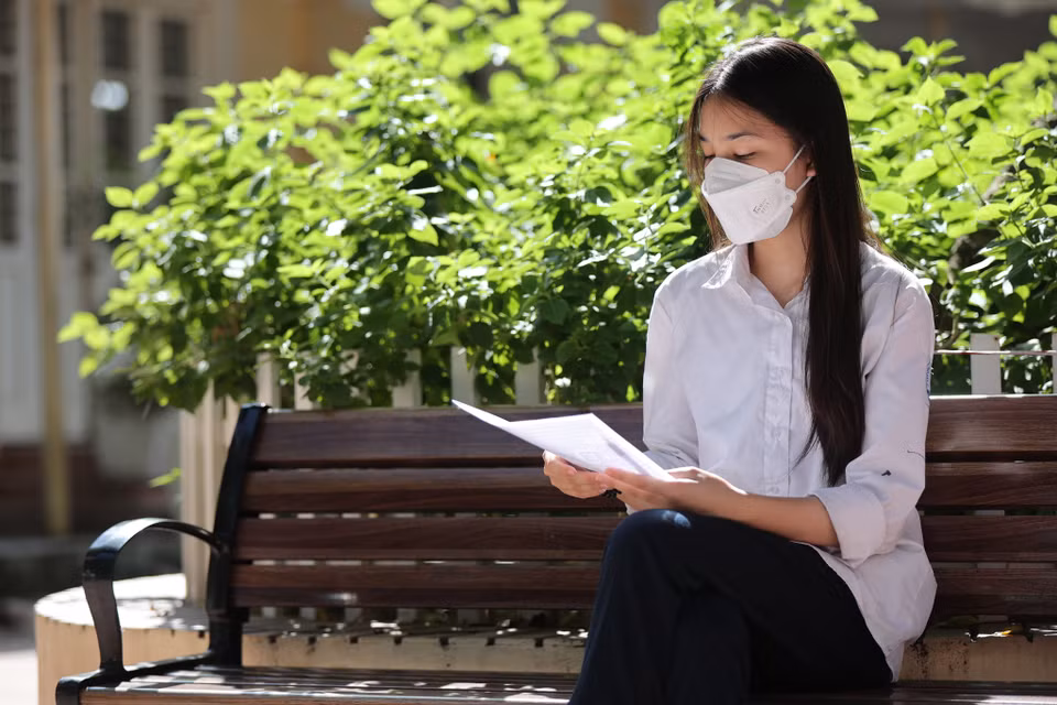 Thí sinh ngồi kiểm tra thông tin cá nhân trước khi vào phòng thi để làm thủ tục đăng ký. (Ảnh: PV/Vietnam+)