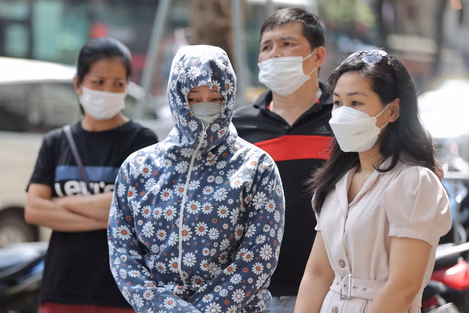 Nhiều bậc phụ huynh đội nắng chờ các con bên ngoài điểm thi. (Ảnh: PV/Vietnam+) 