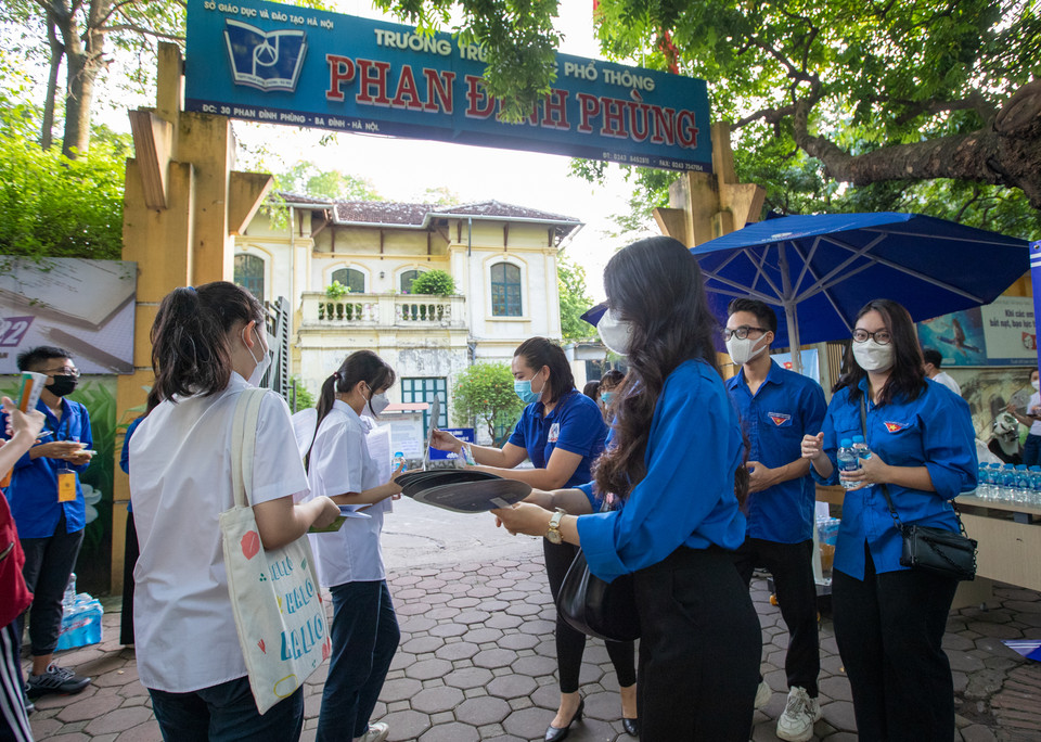 Tình nguyện viên phát quạt chống nóng cho các thí sinh. (Ảnh: PV/Vietnam+)